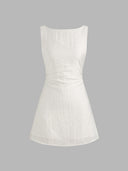 Woman wearing an ivory boat-neck mini dress with a knotted backless detail