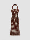 Woman wearing a chocolate polka dot midi dress with a halter choker neckline