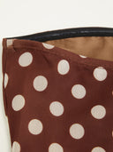 Woman wearing a chocolate polka dot midi dress with a halter choker neckline