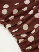 Woman wearing a chocolate polka dot midi dress with a halter choker neckline