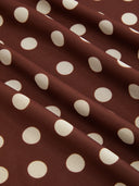 Woman wearing a chocolate polka dot midi dress with a halter choker neckline