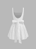 Woman wearing an ivory floral jacquard mini dress with a backless bow detail