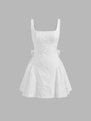 Woman wearing an ivory floral jacquard mini dress with a backless bow detail