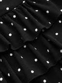 Woman wearing a black polka dot mini dress with a tiered ruffle skirt