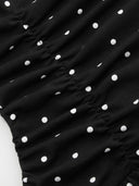 Woman wearing a black polka dot mini dress with a tiered ruffle skirt