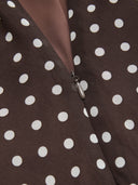 Woman wearing a dark brown polka dot midi dress with a matching scarf
