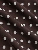 Woman wearing a dark brown polka dot midi dress with a matching scarf