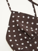 Woman wearing a dark brown polka dot midi dress with a matching scarf