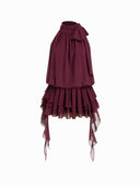 Woman wearing a wine burgundy mini dress with an asymmetric handkerchief hem