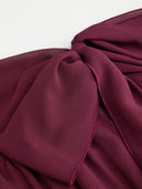 Woman wearing a wine burgundy mini dress with an asymmetric handkerchief hem