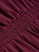 Woman wearing a wine burgundy mini dress with an asymmetric handkerchief hem