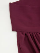 Woman wearing a wine burgundy mini dress with an asymmetric handkerchief hem