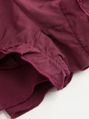 Woman wearing a wine burgundy mini dress with an asymmetric handkerchief hem