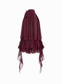 Woman wearing a wine burgundy mini dress with an asymmetric handkerchief hem