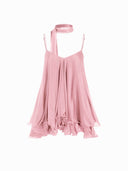 Woman wearing a pink tiered ruffle mini dress with a matching scarf