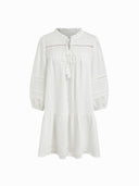 Woman wearing a white cotton mini dress with lace insets and puff sleeves