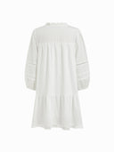 Woman wearing a white cotton mini dress with lace insets and puff sleeves