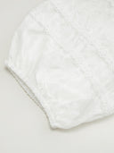 Woman wearing a white cotton mini dress with lace insets and puff sleeves