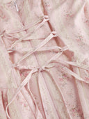 Woman wearing a blush ditsy floral corset midi dress with a lace-up back