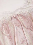Woman wearing a blush ditsy floral corset midi dress with a lace-up back