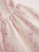 Woman wearing a blush ditsy floral corset midi dress with a lace-up back