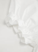 Woman wearing a white babydoll mini dress with a Peter Pan collar and puff sleeves