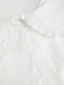 Woman wearing a white babydoll mini dress with a Peter Pan collar and puff sleeves