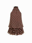 Woman wearing a chocolate brown polka dot halter mini dress with an open back