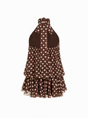 Woman wearing a chocolate brown polka dot halter mini dress with an open back