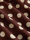 Woman wearing a chocolate brown polka dot halter mini dress with an open back