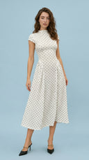 Woman wearing a white dress with black polka dots on a light blue background
