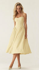 Woman wearing a light yellow dress against a white background