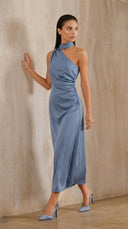 Woman wearing a blue halter neck dress against a beige wall.