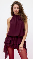 Woman wearing a wine burgundy mini dress with an asymmetric handkerchief hem