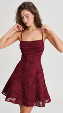 Woman wearing a wine red floral jacquard mini dress with a lace-up back
