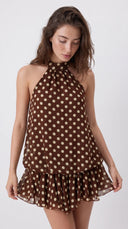 Woman wearing a chocolate brown polka dot halter mini dress with an open back