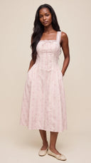 Woman wearing a blush ditsy floral corset midi dress with a lace-up back