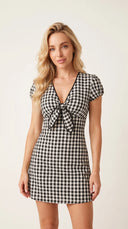 Woman wearing a black gingham mini dress with a twist-knot detail