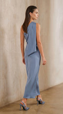 Woman wearing a light blue dress against a beige wall.