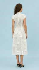 Woman wearing a white dress with black polka dots against a light blue background