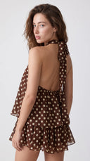 Woman wearing a chocolate brown polka dot halter mini dress with an open back
