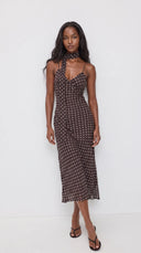 Woman wearing a dark brown polka dot midi dress with a matching scarf