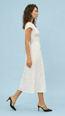 Woman wearing a white polka dot dress against a light blue background