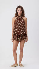 Woman wearing a chocolate brown polka dot halter mini dress with an open back