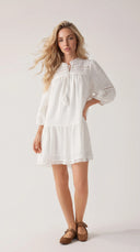Woman wearing a white cotton mini dress with lace insets and puff sleeves