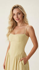 Woman wearing a light yellow dress against a plain background