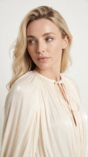 Woman wearing an ivory pleated bishop sleeve mini dress with matching shorts