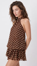 Woman wearing a chocolate brown polka dot halter mini dress with an open back