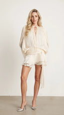 Woman wearing an ivory pleated bishop sleeve mini dress with matching shorts