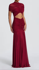 Woman wearing a burgundy ruched cape maxi dress, side view showing the flared skirt